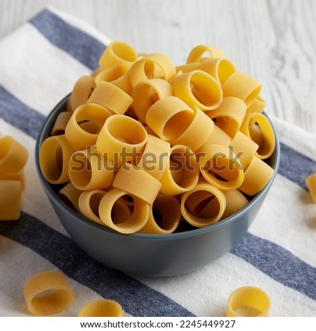 Raw Uncooked Pasta Calamarata in a Bowl, side view.