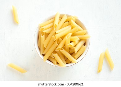 Raw Uncooked Pasta Penne In Bowl Over White Wooden Background