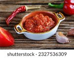 Raw uncooked Salsa or adjika sauce is traditional Mexican or Caucasus Armenian sauce with tomatoes and hot chili peppers on wodden background close up. Concept of vegetarian food