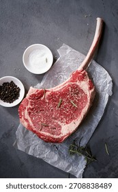 Raw uncooked Tomahawk steak with bone with salt and pepper