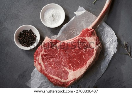Raw uncooked Tomahawk steak with bone with salt and pepper