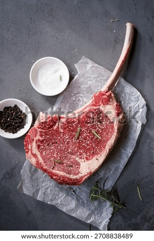 Raw uncooked Tomahawk steak with bone with salt and pepper