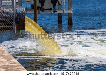 Raw untreated yellow water or sewage being pumped into a blue lake - Hollywood, Florida, USA