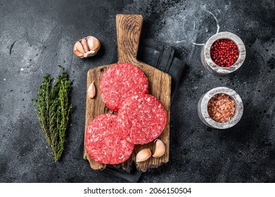 Raw veal hamburger patties with herbs and spices. Black background. Top view - Powered by Shutterstock