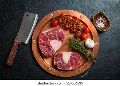 Raw veal shank slices meat and ingredients for Osso Buco cooking on black background, top view