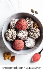 Raw vegan dessert. Energy balls. Truffles made from nuts, seeds, cocoa, dates and various superfood powders, white marble background.