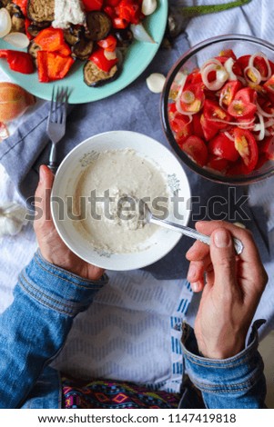 Raw vegan mayonnaise made of blended cashew, sesame seeds, sunflower seeds, mustard powder, unrefined oil, garlic, herbs, spices. Woman hands holds homemade mayonnaise. Vegetarian healthy food