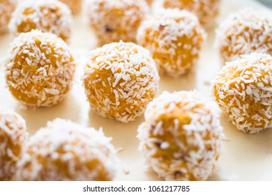 Raw vegan sweet coconut balls. Healthy sweets with dried apricot, dates and coconut meat and oil on plate. Vegetarian food concept.
