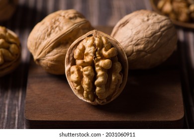 Raw Walnut Kernels And Walnuts On Wooden Background