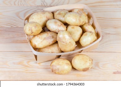 Raw washed yellow young potatoes with unpeeled thin skin in the small wooden basket and beside on the rustic table - Shutterstock ID 1794364303