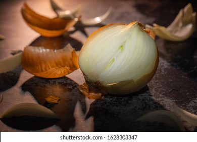 Raw white onion with peeled skins and onion slices with dark background