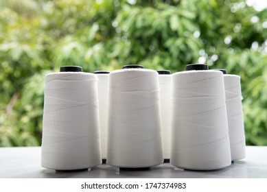 Raw White Polyester FDY Yarn Spool With Green Blurred Background