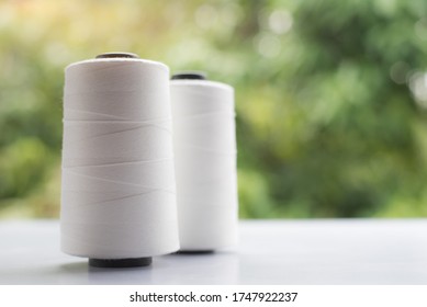Raw White Polyester FDY Yarn spool with blurred green background