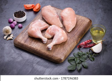 Raw Whole Chicken Leg  And Breast Fillet Without Skin Arranged In A Kitchen Wooden Board And Garnished With Spices, Vegetable Background,cooking Ingrediants  On Grey Or Graphite Texture