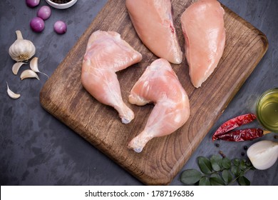 Raw whole chicken leg  and breast fillet without skin arranged in a kitchen wooden board and garnished with spices, vegetable background,cooking ingrediants  on grey or graphite texture