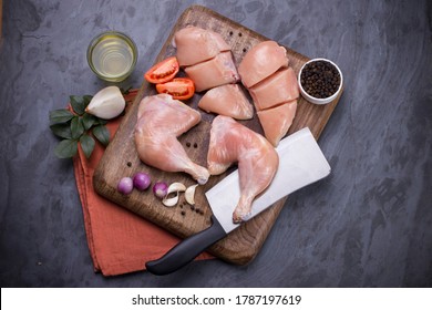 Raw Whole Chicken Leg  And Sliced Breast Fillet Without Skin Arranged On A Kitchen Wooden Board With Knife And Garnished With Spices And  Vegetable ,cooking Ingrediants  On Graphite Texture