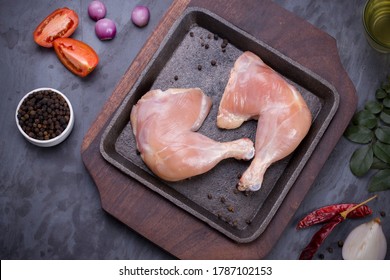 Raw Whole Chicken Leg Without Skin Arranged In An Iron Sizzler Plate With Wooden Base And Garnished With Spices, Vegetable Background,cooking Ingrediants   On Grey Or Graphite Texture