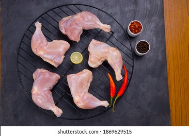 Raw Whole Chicken Leg Without Skin Arranged On A Grill  And Garnished With Lemon Slices,red Chilli Chilli Flakes And Pepper  On Grey Or Graphite Texture Background