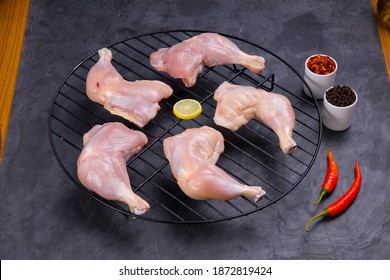 Raw Whole Chicken Leg Without Skin Arranged On A Grill  And Garnished With Lemon Slices,red Chilli Chilli Flakes And Pepper  On Grey Or Graphite Texture Background