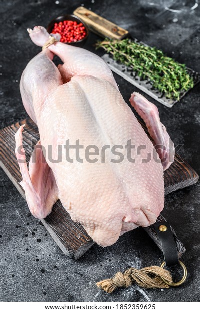 Raw\
whole duck, poultry meat. Black background. Top\
view