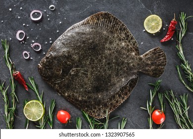 Raw whole flounder fish with rosemary, onions and spices on dark stone background. Creative layout made of fish, top view