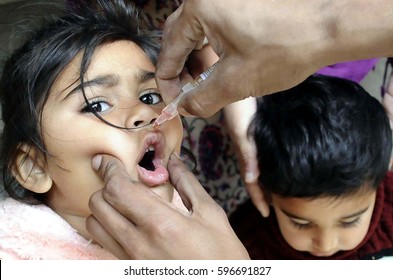 RAWALPINDI, PAKISTAN - MAR 09: Health worker administrates polio-vaccine drops to a child during anti-polio immunization campaign on March 09, 2017 in Rawalpindi.