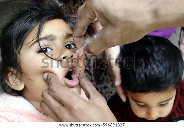 RAWALPINDI, PAKISTAN - MAR 09: Health\
worker administrates polio-vaccine drops to a child during\
anti-polio immunization campaign on March 09, 2017 in\
Rawalpindi.