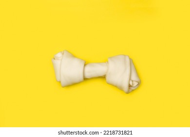 A Rawhide Bone On A Yellow Background With Copy Space