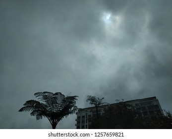 Ray of sun breaking through cloudy weather above building and trees