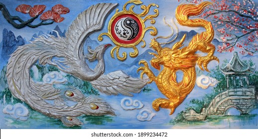 Rayong, Thailand - 16th January, 2021: The yin and yang symbol between a phoenix and a golden dragon, ancient wall decoration at Chinese temple Chao Pho Tho Kong Shrine, eastern Thailand. 