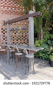 Rayong, Thailand - 19th February, 2021: Rustic breakfast bar with overhanging beam and bar stools for customers outdoors in a garden at Prompt Cafe, a loft style coffee shop in eastern Thailand.