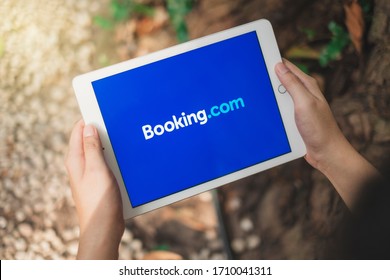 RAYONG, THAILAND, APR 12,2020 : Asian Man Holding Apple Ipad To Use Booking.com Application To Reserve Flight And Hotel For Vacation.

