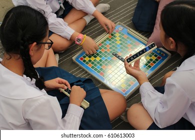 RAYONG, THAILAND, CIRCA DECEMBER 2016, A Group Of Primary School Girls Play A Math Scrabble Style Board Game On The Floor