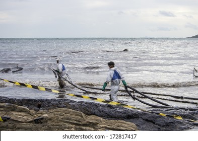 RAYONG, THAILAND - JULY 31, 2013: Workers remove crude oil from the Ao Proa beach, Koh Samet Island, Rayong province, Thailand.