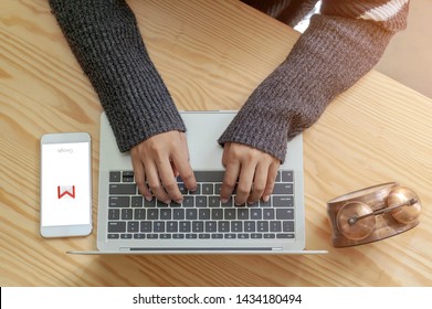 Rayong, THAILAND, June 20, 2019 : Hands on the keyboard close up. View from above. Woman is working at the computer. Near the mobile phone on the screen is a symbol of gmail.