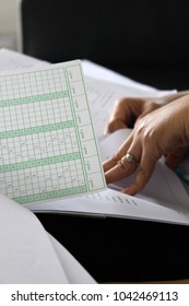 Rayong, Thailand - March 10th, 2018: Close Up Detail Of A Teacher's Hand Grading A Bundle Of School Student Exam Papers And Answer Sheets At The End Of Term.