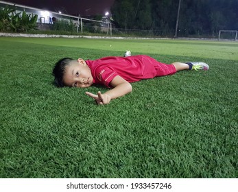 Rayong,Thailand,FEBRUARY 26,2021 : Thai Child 6 Years Old Hands Up To Fight With Resting On Artificial Grass In Soccer Field After Practice Skill Football In Thailand