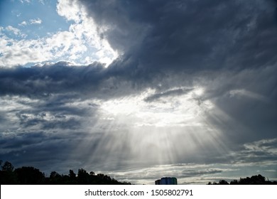 Rays Of Bright Sun Peep Out From Behind Dark Clouds, Sun Break After Storm.