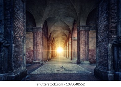 Rays of divine light illuminate old arches and columns of ancient buildings. Bologna, Italy. Conceptual image on historical, religious and travel theme.
