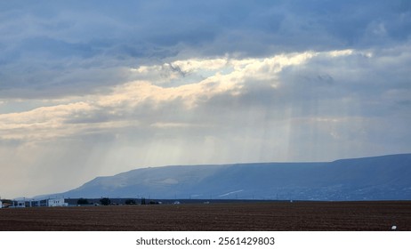 Rays of light shine through an open window in the sky between the winter stormy clouds over Israel, the Holy Land