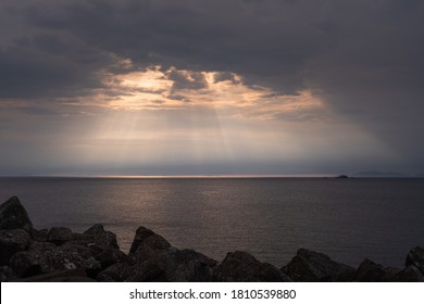 Rays Of Light Shining Through Dark Clouds On Sea During Sunset