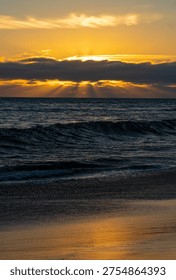 Rays of light shining through some clouds as the Sun sets over the Pacific Ocean.