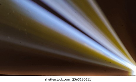 Rays of light spread diagonally creating dynamic patterns on dark walls. A dramatic combination of artistic light and shadow.