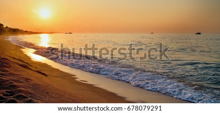 The rays of the rising sun over the Mediterranean Sea with water mist in the background in Malgrat de Mar in Spain. Sun and sand, Mediterranean sea with sea waves, Sunrise and rays,