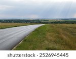 Rays of the setting sun over the valley, the road descends from the hill, evening rural landscape, Volgograd region, right bank of the Don River, Russia