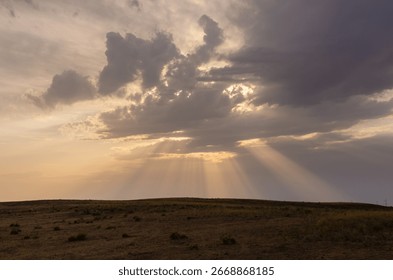 the rays of the sun breaking through the clouds over the hill