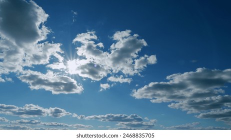 Rays of sun through clouds. Blue sky with cloudscape backlit bright sunlight through summer. Timelapse.