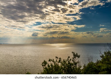 The rays of the sun through the clouds draw spots of light on the surface of the sea.