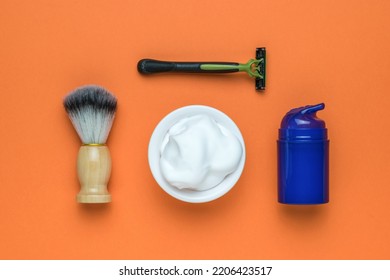 Razor, Brush, Gel And A Bowl With Foam On An Orange Background. Minimal Concept Of Men's Cosmetics. Flat Lay.