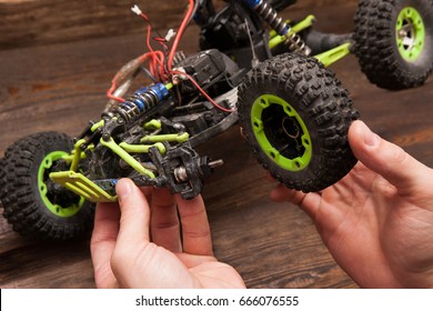 Rc radio control car crawler model repair on wooden background. Green toy suv in repairshop workplace, free space